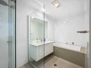 a white bathroom with a sink and a shower at 4BR Cozy house 5mins to beach in Gold Coast