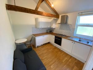 a small kitchen with white cabinets and a blue couch at 3 BEDROOMS WITH 2 PARKING SPACES in Brighton & Hove