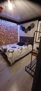 1 dormitorio con cama y pared de ladrillo en La maison d hôte d emmanuelle, en Saint-Antoine-la-Forêt