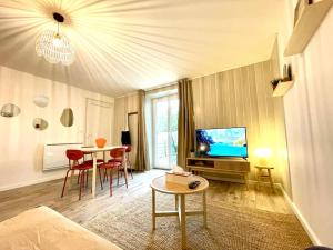 sala de estar con sofá, mesa y TV en Grand Studio Chez Soi - Queen size bed - Terrasse, en Oyonnax