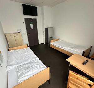 a room with two beds and a desk at Arena Hostel & Monteurzimmer in Hamburg