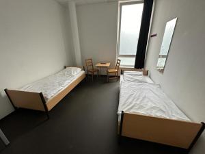 ハンブルクにあるArena Hostel & Monteurzimmerのベッド2台、テーブル、椅子が備わる客室です。