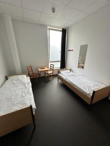 a room with two beds and a table and chairs at Arena Hostel & Monteurzimmer in Hamburg