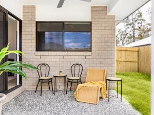 a patio with chairs and tables in front of a brick wall at Well decorated cozy 3BR home at Browns Plain in Browns Plains