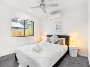 a bedroom with a large white bed with two lamps at Brand New 2BR well designed home at Brown Plains in Browns Plains