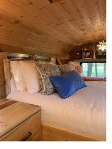 Una cama en una cabaña con almohadas. en Purdon Groves Wanderlust Skoolie, 