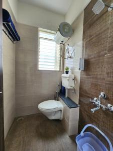 a bathroom with a toilet and a sink and a window at Trinity Stays Nashik - Mountain view apartment close to Sula in Nashik