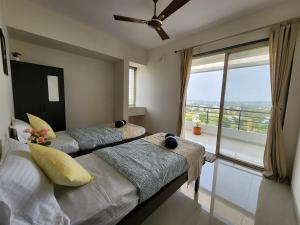 two beds in a room with a large window at Trinity Stays Nashik - Mountain view apartment close to Sula in Nashik
