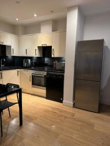 eine Küche mit einem Kühlschrank aus Edelstahl und einem Tisch in der Unterkunft studio flat in streatham in London