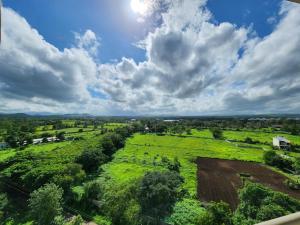an aerial view of a field under a cloudy sky at Trinity Stays Nashik - Mountain view apartment close to Sula in Nashik