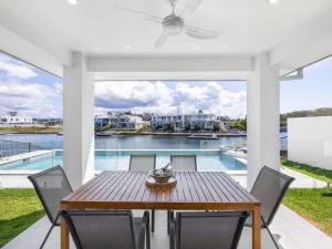 a patio with a table and chairs and a pool at Stunning waterfront family home with pontoon newly in Gold Coast