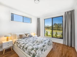 a white bedroom with a bed and a large window at Stunning waterfront family home with pontoon newly in Gold Coast