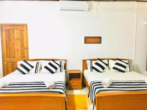 a room with two beds with black and white pillows at Aura City Hostel in Anuradhapura