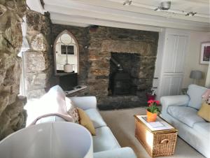 a living room with a couch and a stone fireplace at Samphire Cottage in Helston