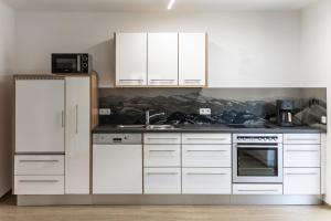 a kitchen with white cabinets and a sink at Appartement Monika in Neukirchen am Großvenediger