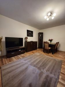 een woonkamer met een flatscreen-tv en een tafel bij Słoneczny apartament 2 in Duszniki Zdrój