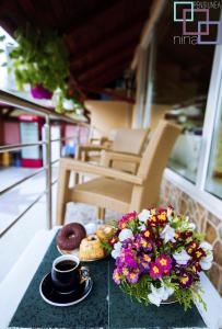 una mesa con una taza de café y flores. en Pension Nina, en 23 August