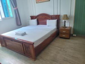 sypialnia z drewnianym łóżkiem i szafką nocną w obiekcie FUN HOTEL w Ho Chi Minh +1 zdjęcie