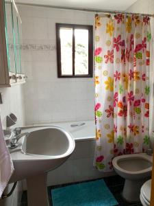 ein Badezimmer mit Waschbecken, Toilette und Duschvorhang in der Unterkunft Casa Elena in Villa Gesell + 25 Fotos
