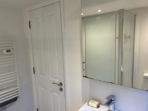 uma casa de banho branca com um espelho e um lavatório em Lovely Self Contained Loft Studio - 33AS4 em Londres