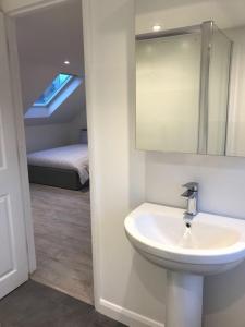 a bathroom with a sink and a room with a bed at Lovely Self Contained Loft Studio - 33AS4 in London