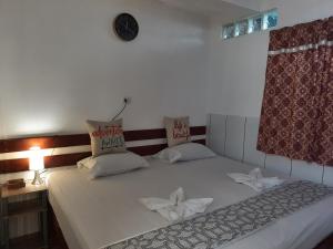 een slaapkamer met een wit bed met een klok aan de muur bij Amazon House Hostel in Iquitos