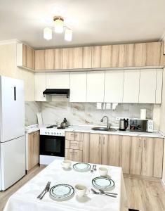 a kitchen with wooden cabinets and white appliances at Аэропорт ЖК Алтын сити in Almaty