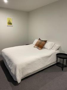 a bedroom with a white bed with a pillow and a stool at Beckford House in Methven