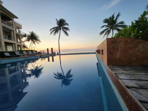 uma piscina com palmeiras num resort em Ocean Front El Faro Reef 304 em Playa del Carmen