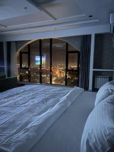 een slaapkamer met een groot bed en uitzicht op de stad bij Hotel Panorama in Doesjanbe