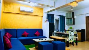 a living room with a blue couch and a table at Luxurious Spacious 2 BHK With Pool Wi-Fi Cooking Gas Gym in Calangute