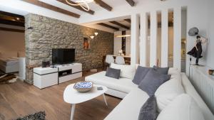 een woonkamer met een witte bank en een stenen muur bij Archhouse in Kalabaka