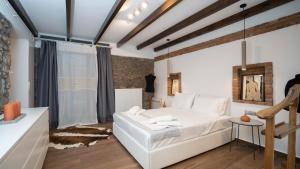 een slaapkamer met een wit bed en een tafel bij Archhouse in Kalabaka