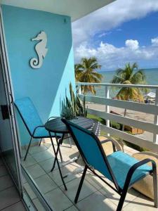 a balcony with two chairs and a seahorse sign on it at Hermoso Estudio frente al mar Ocean Blue Faith in Fajardo