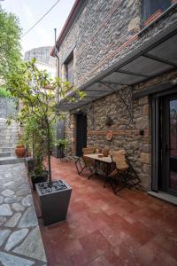 een patio met een tafel en stoelen en een bakstenen gebouw bij Archhouse in Kalabaka