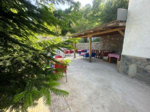 a patio with red chairs and tables and a stone building at Guest House BOZVILL in Bozovec