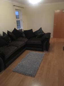 a living room with a black couch and a rug at Lovely Two bed flat located in the heart of Dunstable in Dunstable