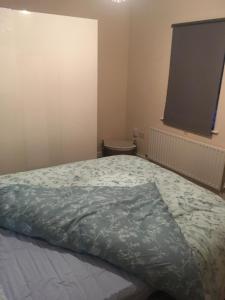 a bedroom with a bed with a blue comforter at Lovely Two bed flat located in the heart of Dunstable in Dunstable