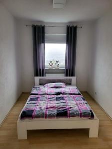a bed in a room with a window with a bedspread at schöne, modernisierte Wohnung - Dudweiler in Saarbrücken