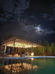 una pérgola con luces junto a una piscina por la noche en Ecopark Hosteria Puyo, en Puyo