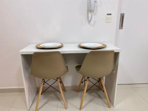 a white table with two chairs and plates on it at O melhor apartamento no shopping in Águas Claras