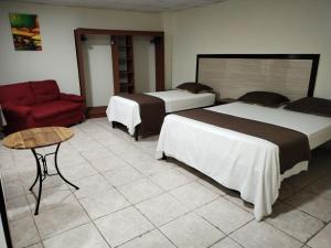 um quarto de hotel com duas camas e uma cadeira vermelha em Hotel America - La Chorrera em La Chorrera