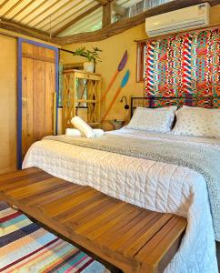 a bedroom with two beds and a wooden bench at Casas D’Água Doce - Casa da Árvore in Ilhabela