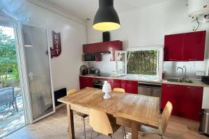 eine Küche mit einem Holztisch und roten Schränken in der Unterkunft Maison, 2chambres, jardin, parking, central,6pers in Montpellier