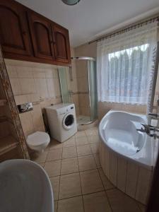 uma casa de banho com uma banheira, um WC e um lavatório. em Domek nad stawem z balią i sauną em Suleczyno
