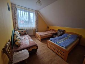 a small bedroom with two beds and a window at Domek nad stawem z balią i sauną in Sulęczyno