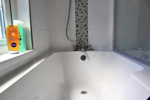 uma banheira branca na casa de banho com uma janela em Victoria 4 bedroom Serviced House Short Lets - Near Northampton Gen Hosp & Town Centre em Northampton