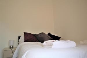Una cama blanca con un montón de almohadas. en Victoria 4 bedroom Serviced House Short Lets - Near Northampton Gen Hosp & Town Centre, en Northampton