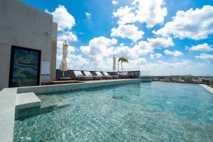 a swimming pool on the roof of a building at Kippal - Modern Oasis - ApartHotel in Cozumel