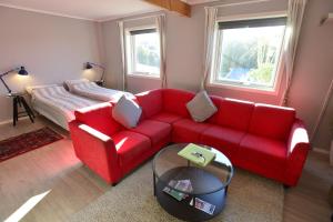 ein Wohnzimmer mit einem roten Sofa und einem Bett in der Unterkunft Guesthouse in Manger, Radøy Island in Kollstad